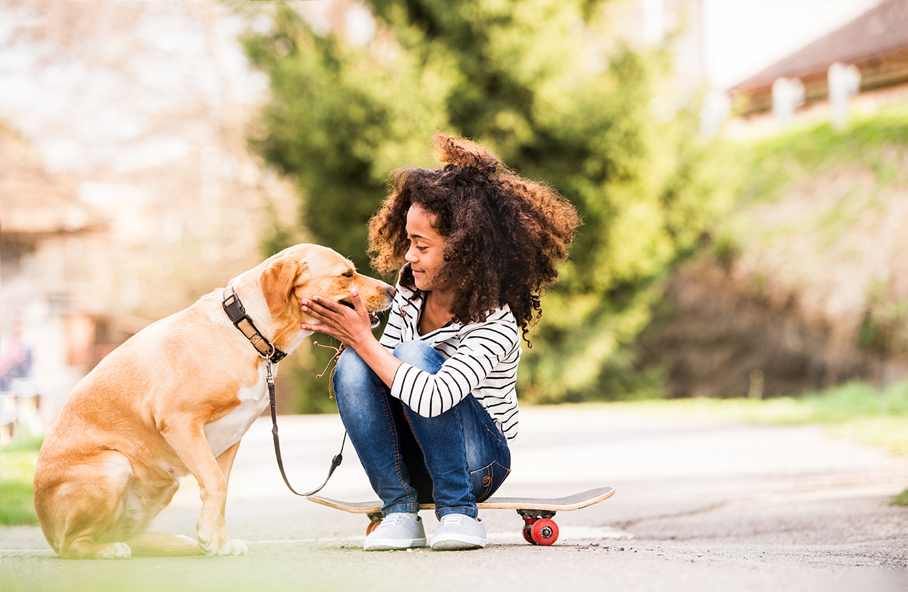 African-american-girl-outdoors-on-skateboard-with-her-dog
